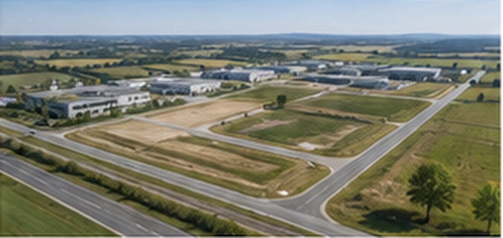 Luftbild eines kleineren Gewerbeparks mit Hallen und freien Flächen